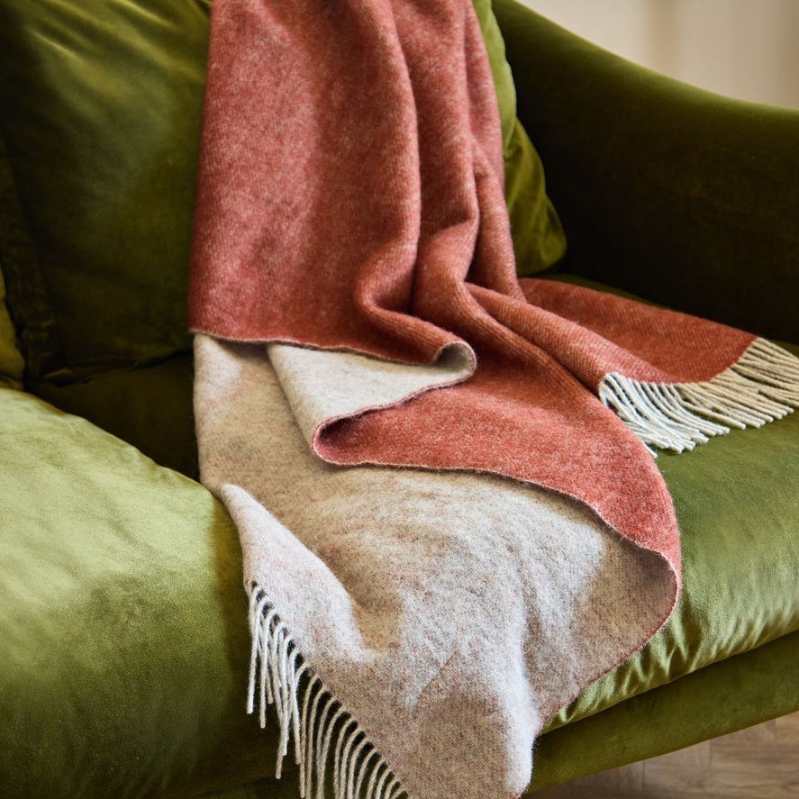 Dartmoor pure new wool throw in red -oat colour draped over sofa